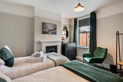 a bedroom with two beds and a chair and a fireplace at 3 Bed in Felixstowe oc-s27808 in Felixstowe