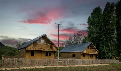 two wooden houses with a fence and a cloudy sky at Owls Nest in Larling