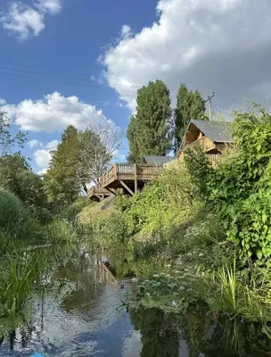 a wooden bridge over a river with a house at Owls Nest in Larling