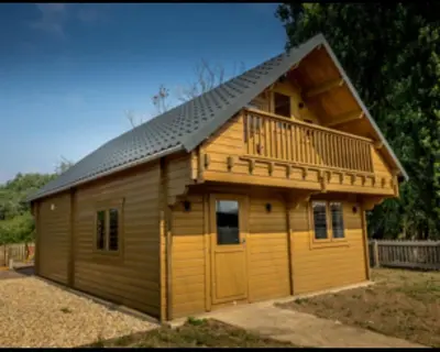 a large wooden cabin with a balcony and a deck at Owls Nest in Larling