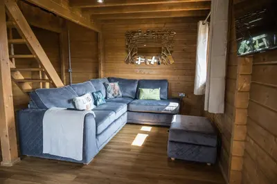 a living room with a blue couch in a cabin at Owls Nest in Larling