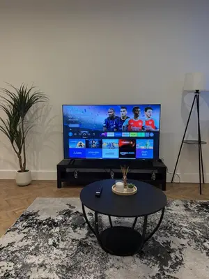 a living room with a table and a large screen television at Luxury Modern Apartment in Central Chelmsford in Chelmsford