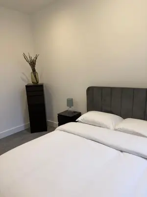 a bedroom with a white bed and a vase on a table at Luxury Modern Apartment in Central Chelmsford in Chelmsford