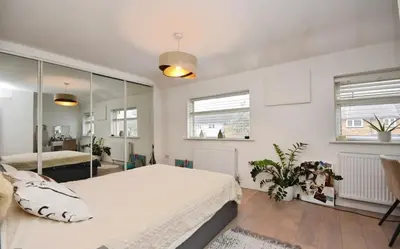 a bedroom with a large white bed and two windows at House in Harold Wood in Harold Wood