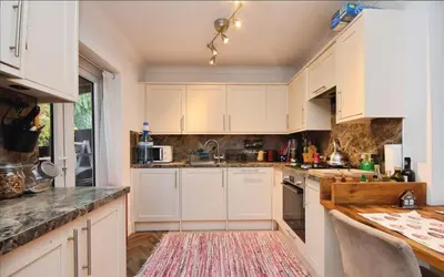 a kitchen with white cabinets and a red rug at House in Harold Wood in Harold Wood