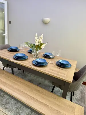 a wooden table with blue plates and wine glasses at The Opulent Property Project Southend 4 Bed Sleeps 7 in Southend-on-Sea