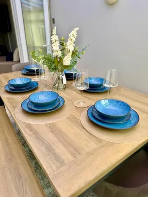 a wooden table with blue plates and wine glasses at The Opulent Property Project Southend 4 Bed Sleeps 7 in Southend-on-Sea