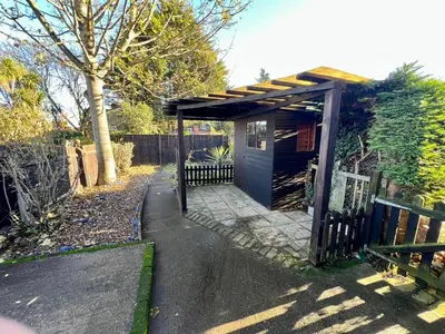 a small blue shed with a fence in a yard at Spacious 3 bedroom house in Central Leiston in Leiston