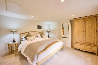 a bedroom with a large bed and a wooden cabinet at Host & Stay The Coral Cottage in Wymondham