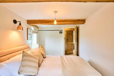 a bedroom with a white bed and a wooden ceiling at Host & Stay The Coral Cottage in Wymondham