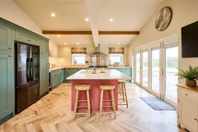 a kitchen with blue cabinets and a island with bar stools at Host & Stay The Coral Cottage in Wymondham