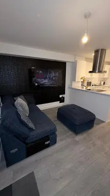 a living room with a blue couch and a kitchen at Private Kingsize Bedroom in Horndon on the Hill