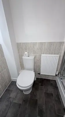 a bathroom with a white toilet and a radiator at Private Kingsize Bedroom in Horndon on the Hill