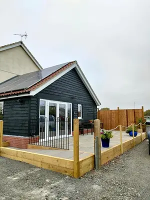 a small black house with a wooden deck at Townfield Lodge in Bury Saint Edmunds