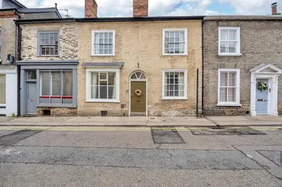 a brick house with a yellow door on a street at Charming Guildhall street - sleeps up to 6 guests in the Medieval Grid in Bury Saint Edmunds