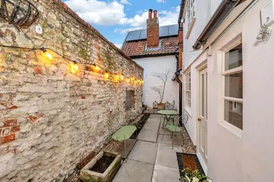 a stone wall with a table and chairs in a courtyard at Charming Guildhall street - sleeps up to 6 guests in the Medieval Grid in Bury Saint Edmunds