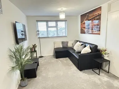 a living room with a black couch and a plant at Cosy one bed Flat in Stevenage in Stevenage