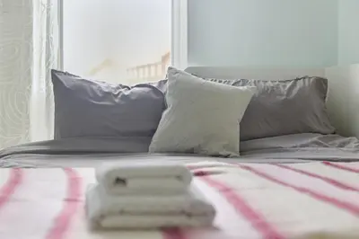 a bed with two pillows and a towel on it at Steps from Train Station - Modern 2-Bedroom with Balcony & Cambridge Amenities, Family Friendly in Cambridge