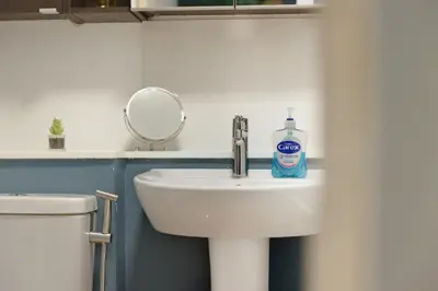 a bathroom sink with a bottle of soap on it at Steps from Train Station - Modern 2-Bedroom with Balcony & Cambridge Amenities, Family Friendly in Cambridge