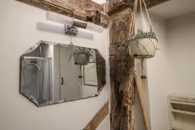 a mirror hanging on a wall with a wooden pole at The Old Post Box in Holton