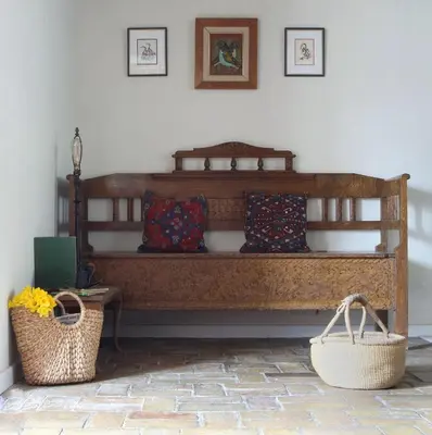 a wooden bench with pillows and baskets in a room at The Old Post Box in Holton
