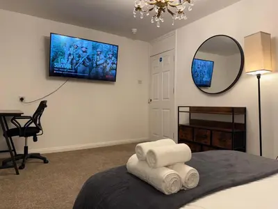 a bedroom with a bed with a mirror and a chair at Stevenage Contractor & Family Retreat in Stevenage