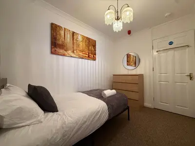 a bedroom with a bed and a mirror and a chandelier at Stevenage Contractor & Family Retreat in Stevenage