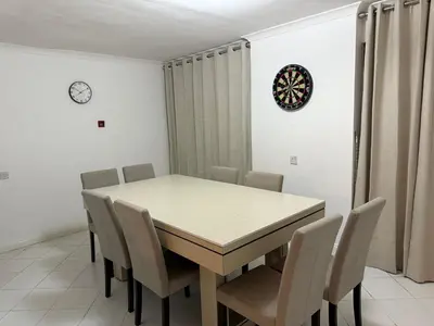 a dining room table with chairs and a clock on the wall at Stevenage Contractor & Family Retreat in Stevenage