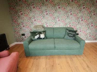 a green couch in a living room with floral wallpaper at The Corn Silo in Ipswich