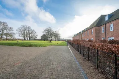 a brick building with a fence next to a field at Ploughman’s Green, Blythburgh in Halesworth