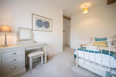 a bedroom with a bed and a desk with a mirror at Ploughman’s Green, Blythburgh in Halesworth