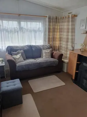 a living room with a couch in front of a window at Hutleys Caravan Holiday Home - St Osyth - Clacton-on-Sea in Saint Osyth
