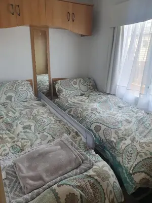 a small bedroom with two beds and a mirror at Hutleys Caravan Holiday Home - St Osyth - Clacton-on-Sea in Saint Osyth