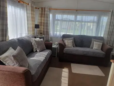 a living room with two couches and a window at Hutleys Caravan Holiday Home - St Osyth - Clacton-on-Sea in Saint Osyth