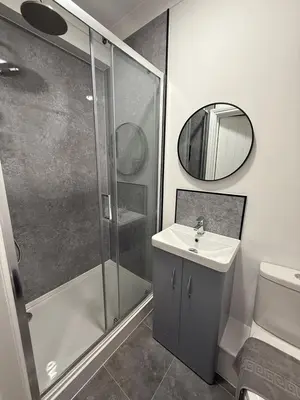 a bathroom with a shower and a sink and a mirror at Sleep Hub in Leiston