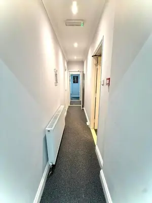 a long hallway with a blue door in a building at Sleep Hub in Leiston