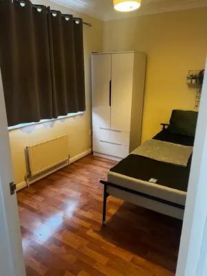 a bedroom with a refrigerator and a wooden floor at Single Room in town house in Rochford