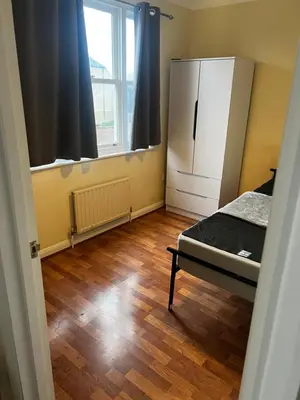 a bedroom with a refrigerator and a wooden floor at Single Room in town house in Rochford