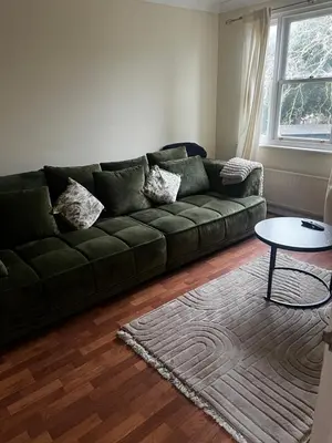 a living room with a green couch and a table at Single Room in town house in Rochford
