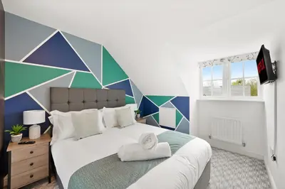 a bedroom with a large bed with a geometric wall at Basildon Premium Crew Stay 4 BR, Sleeps 8, Parking in Laindon