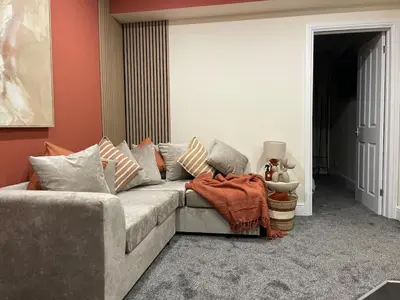 a living room with a gray couch and red walls at Ipswich Hospital Accommodation, Parking & Wifi in Ipswich