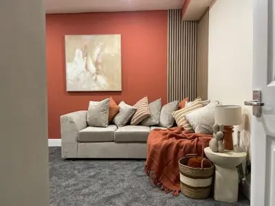 a living room with a couch and an orange wall at Ipswich Hospital Accommodation, Parking & Wifi in Ipswich