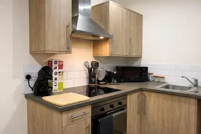 a small kitchen with wooden cabinets and a sink at Ipswich Hospital Accommodation, Parking & Wifi in Ipswich