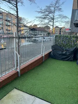 a fence with green grass next to a street at 1 bed flat close to Chelmsford City Centre in Chelmsford
