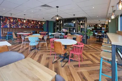 a restaurant with tables and chairs in a room at Travelodge Cambridge Orchard Park in Milton