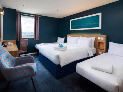 a hotel room with two beds and a chair at Travelodge Ipswich in Ipswich