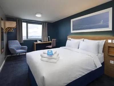 a bedroom with a large bed with towels on it at Travelodge Ipswich in Ipswich