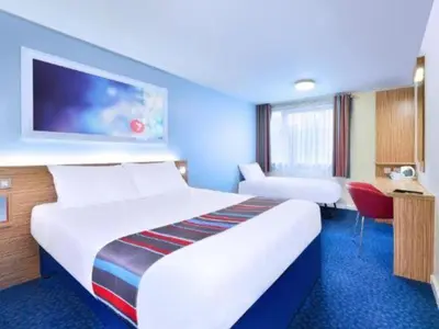 a hotel room with a large bed and a desk at Travelodge Ipswich in Ipswich