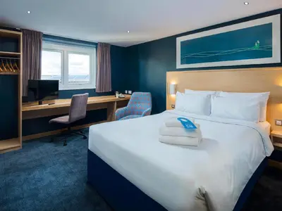 a hotel room with a large bed and a desk at Travelodge Harlow in Harlow