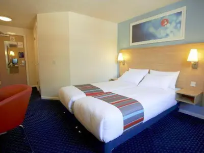 a hotel room with a large bed and a chair at Travelodge Harlow in Harlow